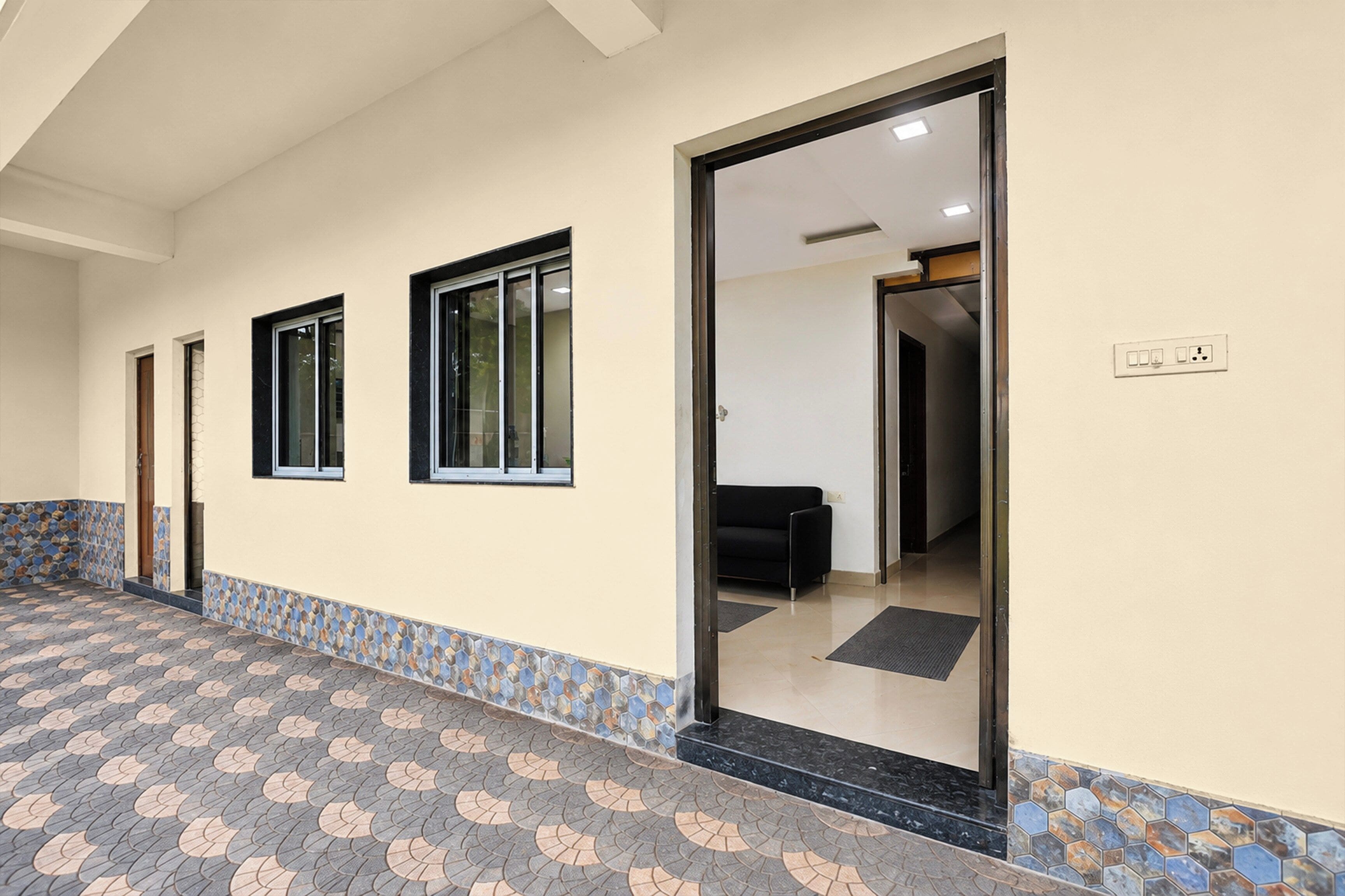 Un pasillo con piso estampado, puertas que dan a habitaciones y un área de descanso con un sofá.