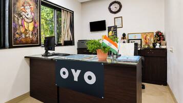 A reception desk with a sign reading 'OYO,' a computer, a plant, and various items on the desk.