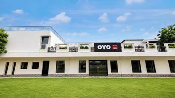 A modern hotel with a flat roof, multiple balconies, and a sign for 'OYO Hotel Amara Palace'.