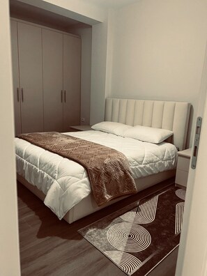 A bedroom with a bed, a wardrobe, and a nightstand. - Ares Home, cozy apartment 8 mins walk from City Centre. (Korçë)