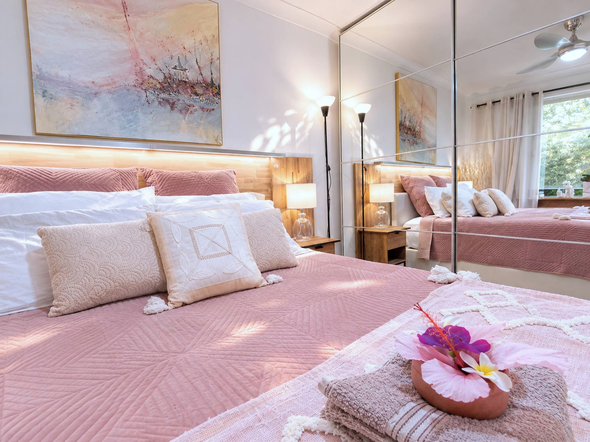 Habitación de hotel con una cama grande, una mesita de noche, un espejo y una ventana con cortinas.