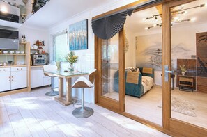 Eine moderne Küche mit Essbereich, eine Schiebetür zu einem Schlafzimmer mit Bett und Bergblick.
