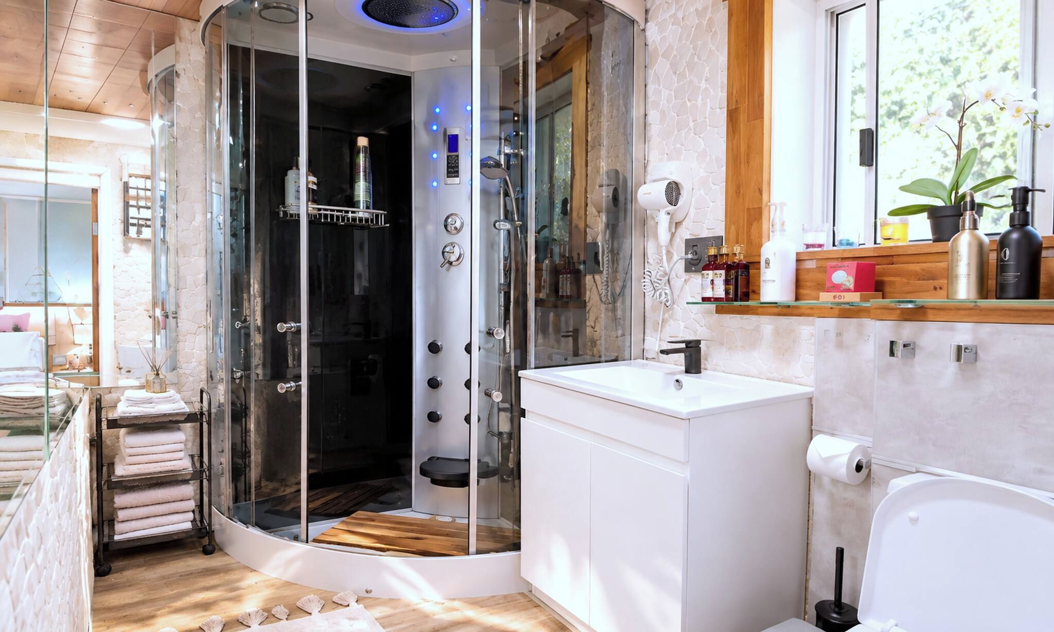 Une salle de bain moderne avec une douche à parois de verre, un lavabo blanc et un meuble-lavabo en bois.