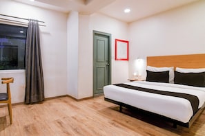 Une chambre d’hôtel avec un lit, une chaise, une porte et une fenêtre avec des rideaux.