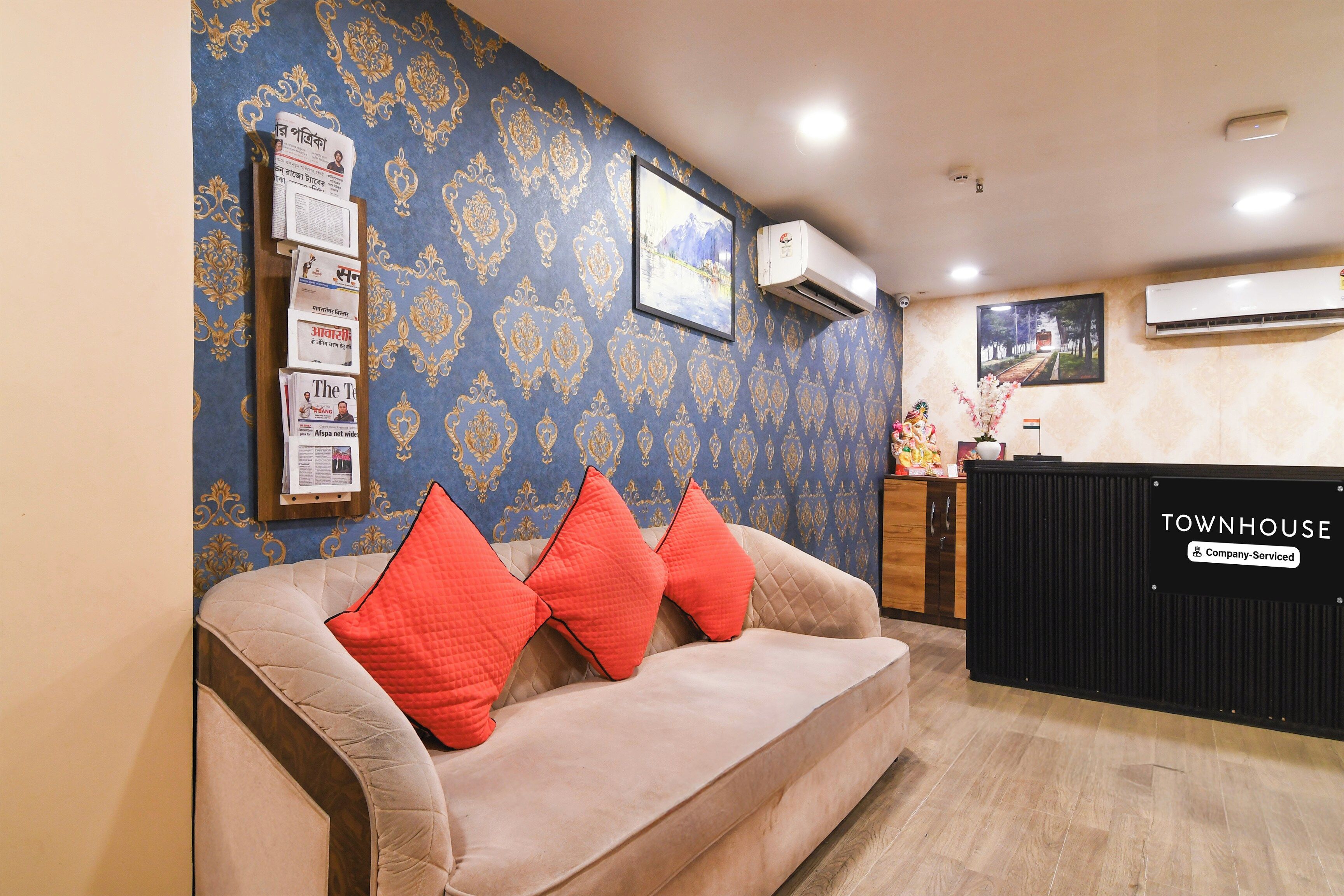 A reception area with a sofa, a black counter, and a wall with patterned wallpaper.