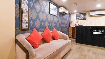 A reception area with a sofa, a black counter, and a wall with patterned wallpaper.