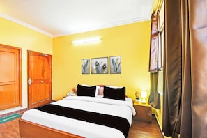 Ein Hotelzimmer mit Bett, Kleiderschrank, Nachttisch mit Lampe und einem Vorhangfenster.