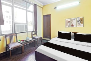 Ein Hotelzimmer mit Bett, Schreibtisch, Stuhl, Fenster und Bildern an der Wand.