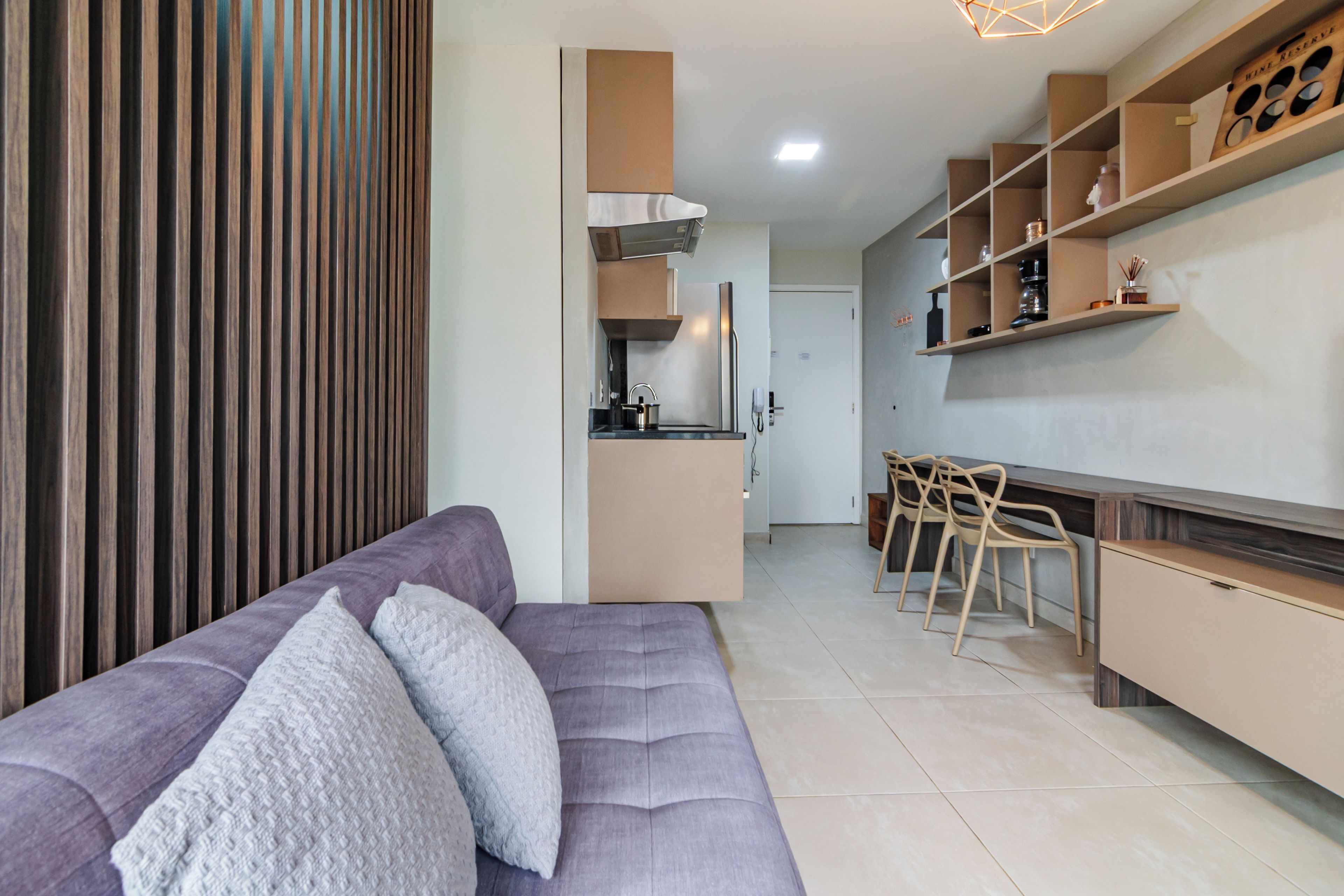 A modern kitchen with a built-in oven, a dining area with a bar counter, and a seating area with a sofa.