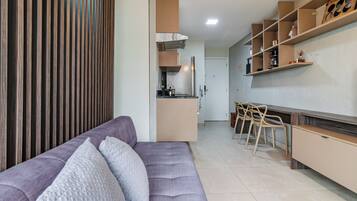 A modern kitchen with a built-in oven, a dining area with a bar counter, and a seating area with a sofa.