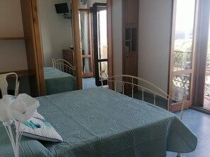 Quarto com duas camas, guarda-roupa de madeira, televisão e varanda com vista.