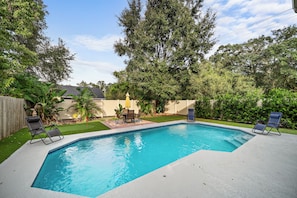 A rectangular swimming pool with a tiled edge, surrounded by a grassy area and a wooden fence. - Heated Saltwater Pool, Pac-Man Arcade, 2 Putting Greens & Tampa Beach Getaway (Tampa)