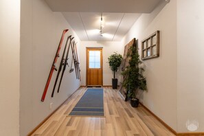 A hallway with wooden flooring, a door at the end, and skis leaning against the wall. - Spacious log cabin by Lake Ihtinkijärvi (Ruka)