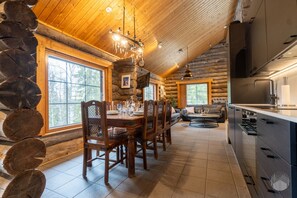 A log cabin interior with a dining area, kitchen, and a large window. - Spacious log cabin by Lake Ihtinkijärvi (Ruka)