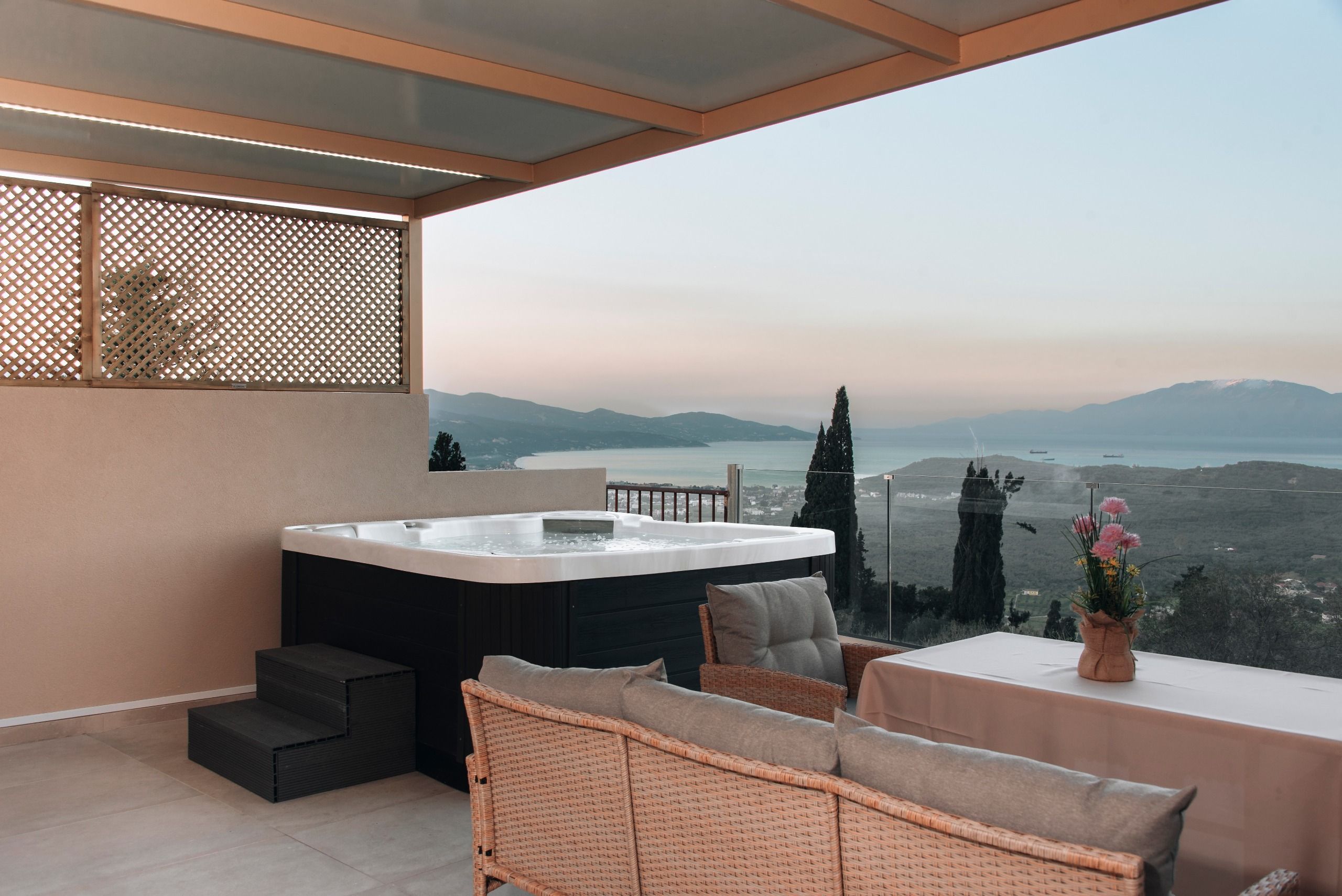 A balcony with a hot tub, wicker furniture, and a view of the landscape.