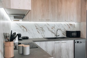A modern kitchen with marble backsplash, wooden cabinets, and a built-in dishwasher. - Magic View Apartment (Zakynthos)