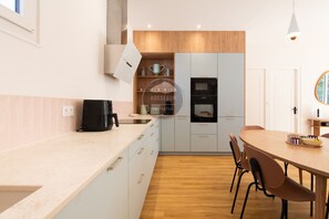 Une cuisine moderne équipée d’un four encastré, d’une machine à café et d’un coin repas avec une table ronde et des chaises.