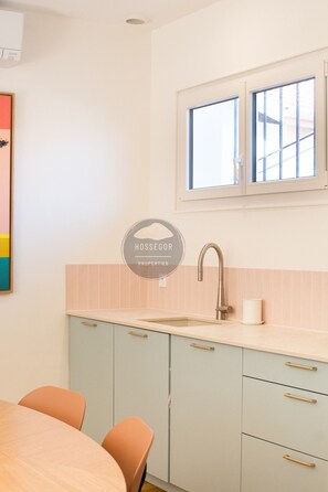 A kitchen with a window above the sink, light-colored cabinets, and a wooden table with chairs. - Villa Goxoki - Capbreton - City Center - Garden (Capbreton)