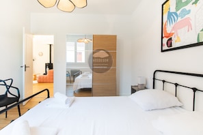 Une chambre moderne avec un grand lit, un mur d’accent en bois et une vue sur une autre pièce.