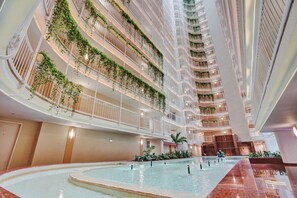A multi-level atrium with a central pool, surrounded by balconies with greenery. - Poolside 2BR | Workspace for two | Gym access (Miami)