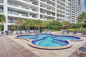 A hotel pool area with multiple lounge chairs and a circular pool. - Poolside 2BR | Workspace for two | Gym access (Miami)