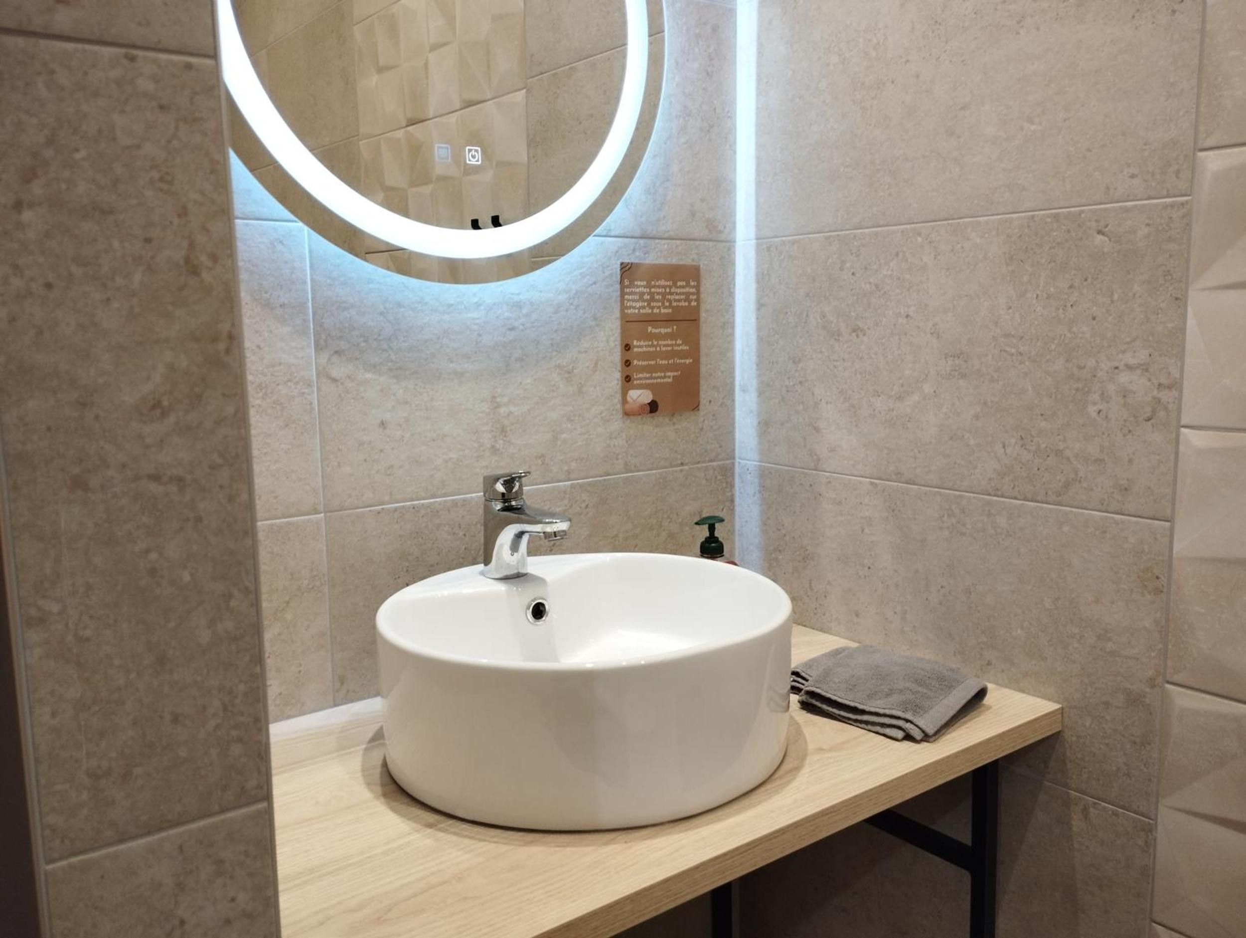 Une salle de bain avec un miroir rond, un lavabo et une serviette posée sur le comptoir.