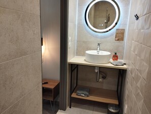 Un baño moderno con un espejo redondo, un lavabo y un perchero para toallas.