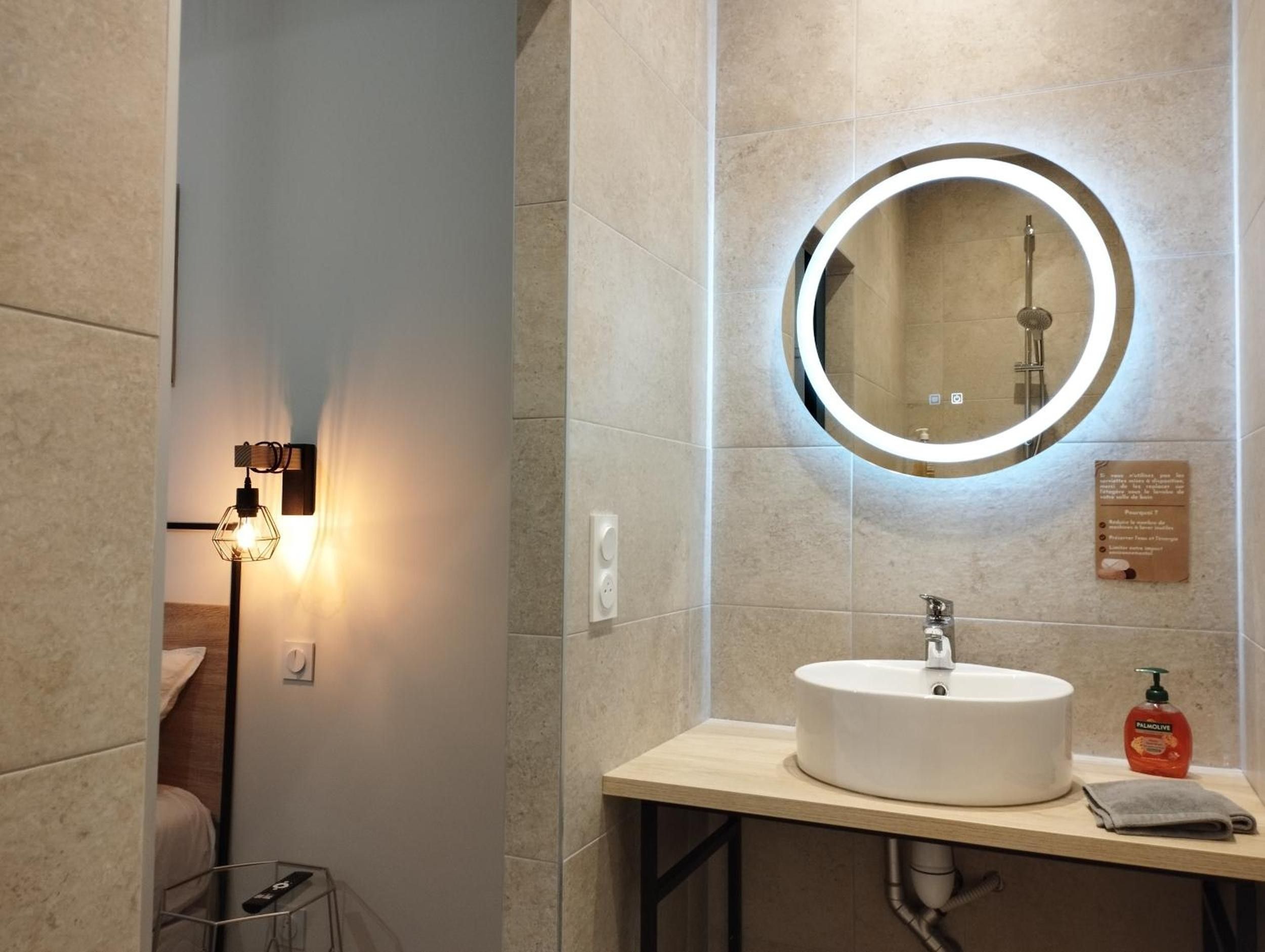 A modern bathroom with a round mirror, a sink, and a towel on the counter.