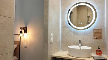 Un baño moderno con un espejo redondo, un lavamanos y una toalla en la encimera.
