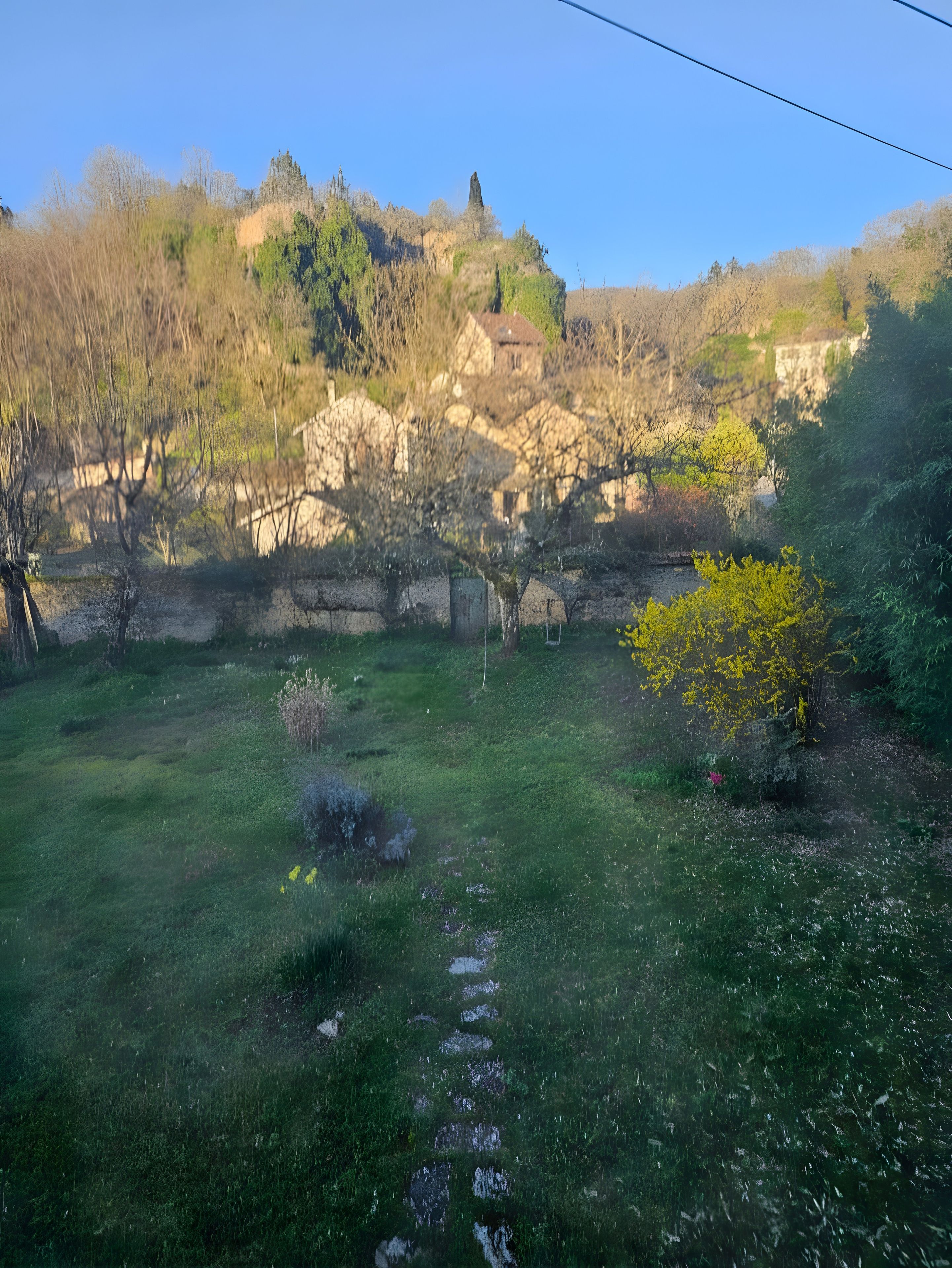 A grassy area with a stone wall and a building in the background.