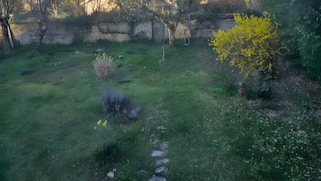 A grassy area with a stone wall and a building in the background.