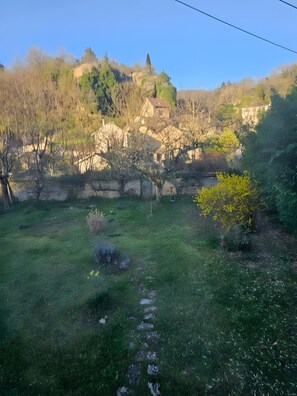 A grassy area with a stone wall and a building in the background. - Apartment 'Coliving Des Moulins Sur Crémieu' with Wi-Fi and Air Conditioning (Crémieu)