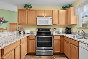 A kitchen with wooden cabinets, a microwave, a stove, and a dishwasher. - 2/2 Well Maintained quiet retreat in the Village of Duval (The Villages)