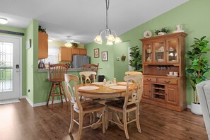 A dining area with a wooden table and chairs, a chandelier, and a wooden cabinet with glass doors. - 2/2 Well Maintained quiet retreat in the Village of Duval (The Villages)