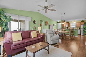 A living room with a leather sofa, a grey armchair, and a wooden coffee table. - 2/2 Well Maintained quiet retreat in the Village of Duval (The Villages)