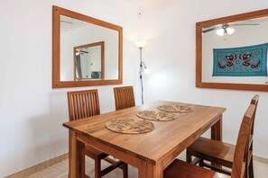 A dining area with a wooden table, four chairs, two wall-mounted mirrors, and a floor lamp. - Villa Buena Vida - Four Bedroom Villa, Sleeps 8 (Playa Blanca)