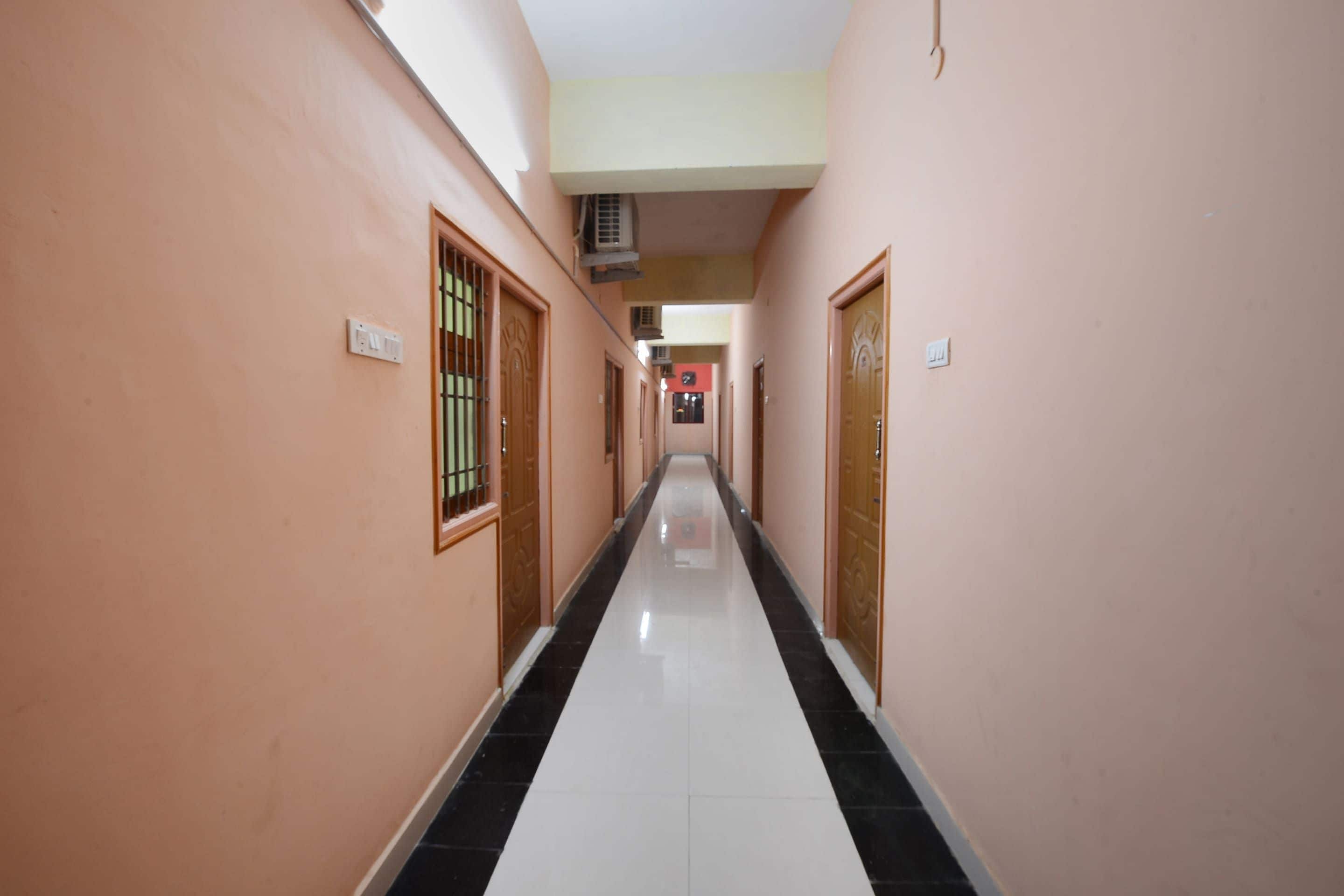A corridor with doors on both sides, a tiled floor, and an air conditioning unit on the wall.