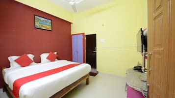 A hotel room with a bed, a wardrobe, a television, and a door.