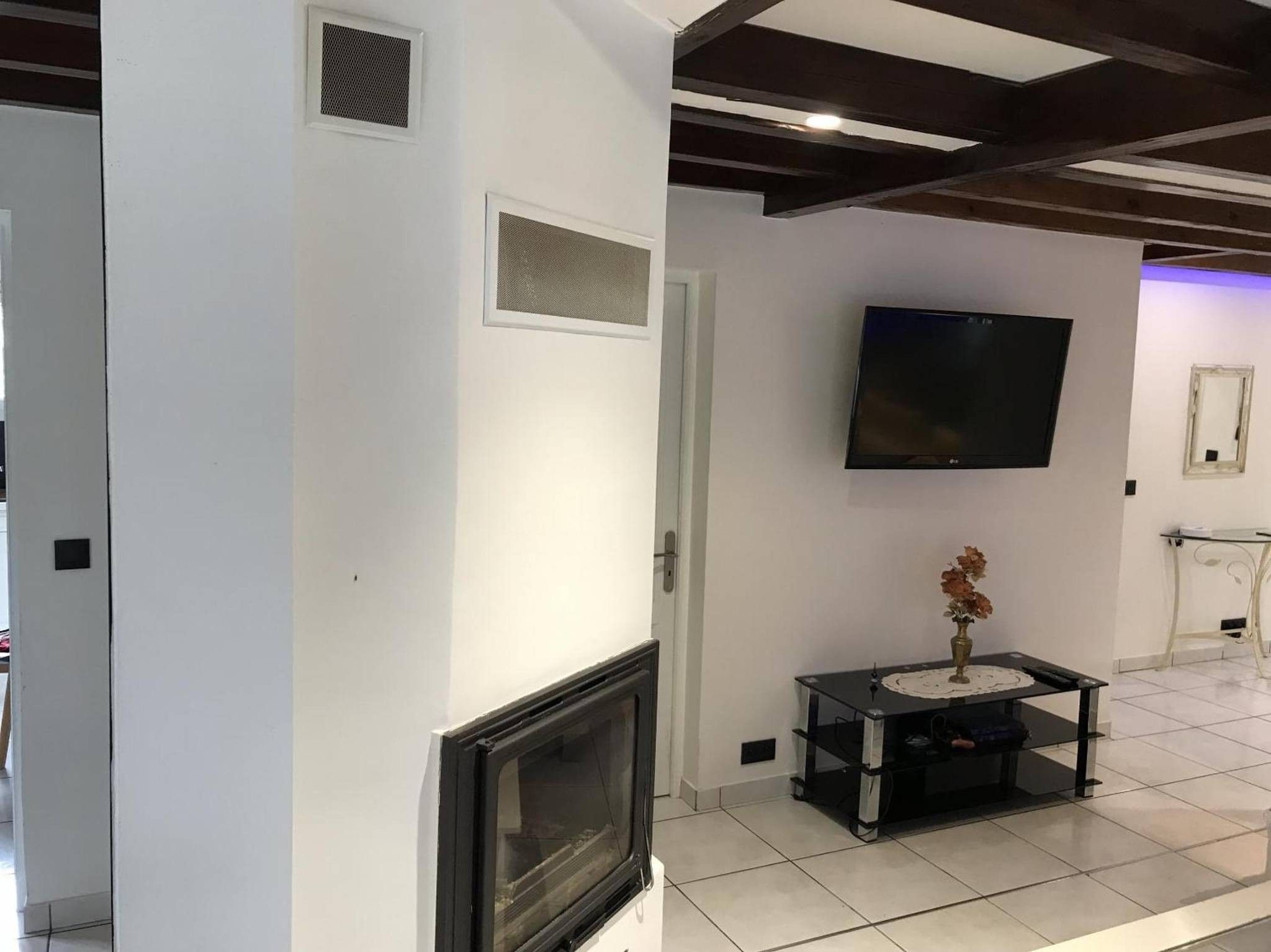 Een moderne woonkamer met een open haard, een flatscreen televisie aan de wand en een kleine tafel met een vaas.