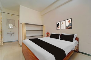 Een hotelkamer met een bed, een nachtkastje, een spiegel, een wastafel en twee ingekaderde foto's aan de muur.