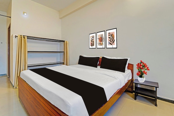 A bedroom with a bed, a nightstand, a wall-mounted shelf, and a window with curtains.