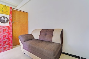 Une pièce avec une porte en bois, une enseigne indiquant « réception », et un canapé placé contre le mur.