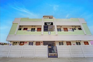 Un edificio de dos pisos con un letrero que indica que es un hotel. Hay varias puertas y ventanas en cada planta.