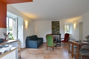 A living room with a sofa, chairs, a fireplace, and a dining area with a table and chairs. - Ker Albiko - entre terre et mer (Ploubalay)