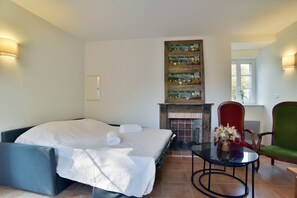 Ein Hotelzimmer mit einem Bett, einem kleinen Tisch mit einer Vase, einem Sessel und einem Kamin.