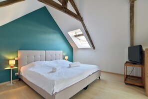 A bedroom with a sloped ceiling, a bed, a television on a stand, and a skylight. - Ker Albiko - entre terre et mer (Ploubalay)