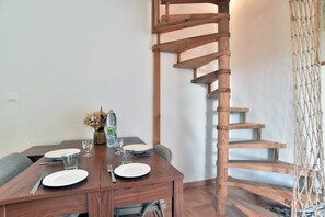 Ein Essbereich mit einer Holztreppe, einem für zwei gedeckten Tisch und einer Wasserflasche auf dem Tisch.