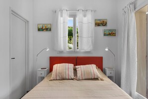 A bedroom with a bed, two bedside tables, a window with curtains, and two wall-mounted paintings. - Villa La Chantyviere - Piscine Privée, Pool House (Sainte-Maxime)