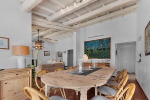Ein Essbereich mit Holztisch und Stühlen, einer Hängelampe und einem Gemälde an der Wand.