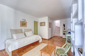 Ein Schlafzimmer mit einem Bett, einer Holzbank, einer grünen Tür und einer Treppe, die in einen anderen Raum führt.